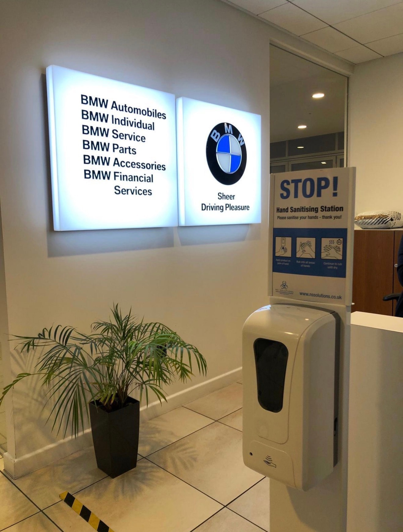 Freestanding alcohol-based hand-gel dispensing station in use at a BMW branch