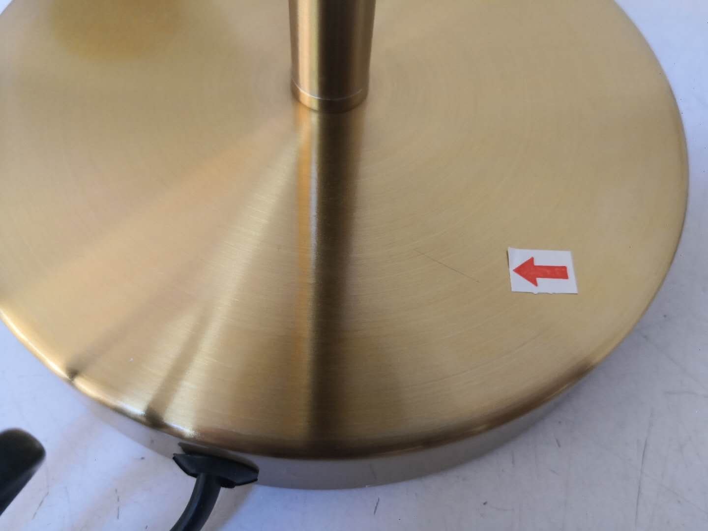 Scratch identified on brushed-brass lamp base during inspection
