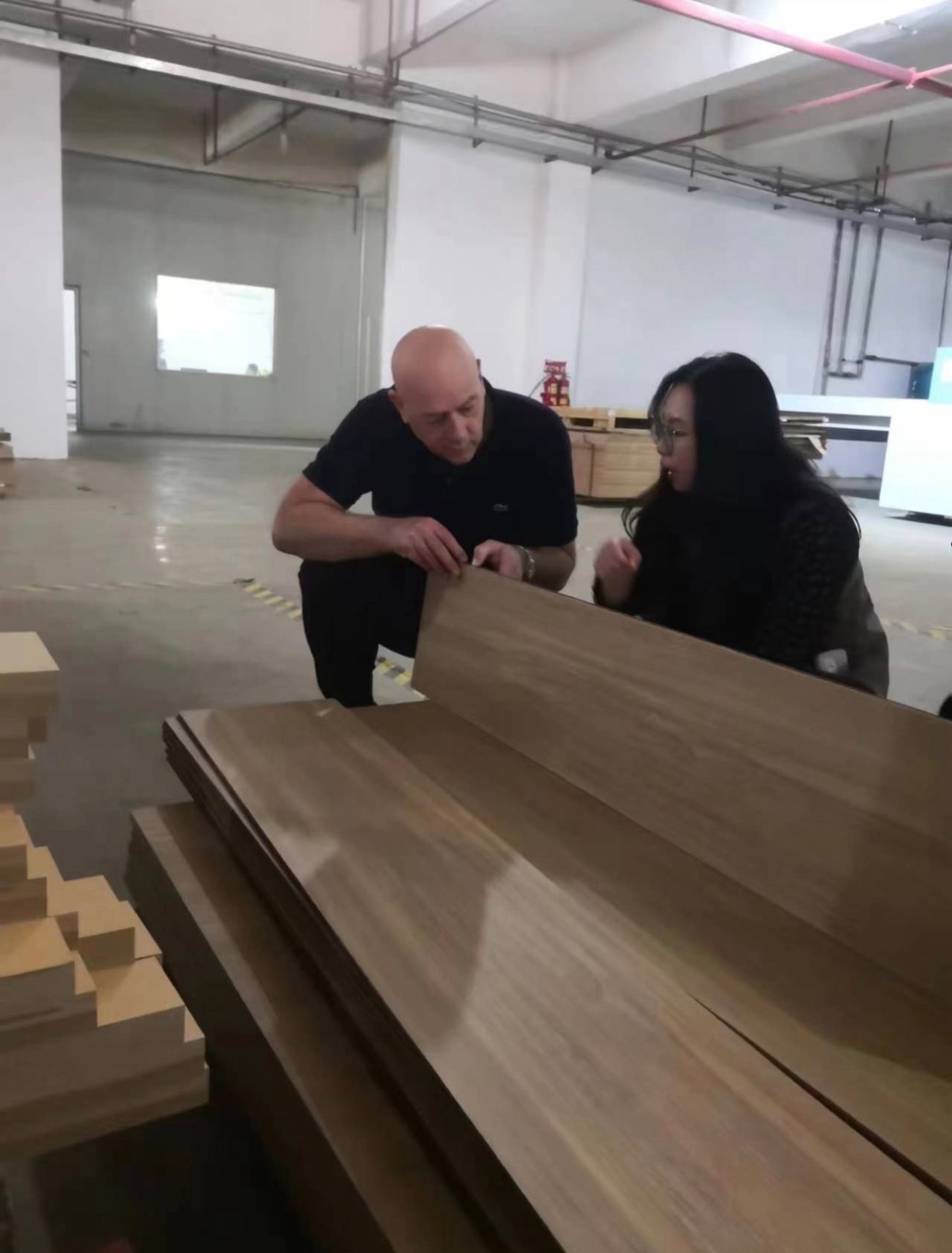 Colin Moore inspecting assembled wooden point-of-sale display units with factory staff at a Chinese manufacturing facility