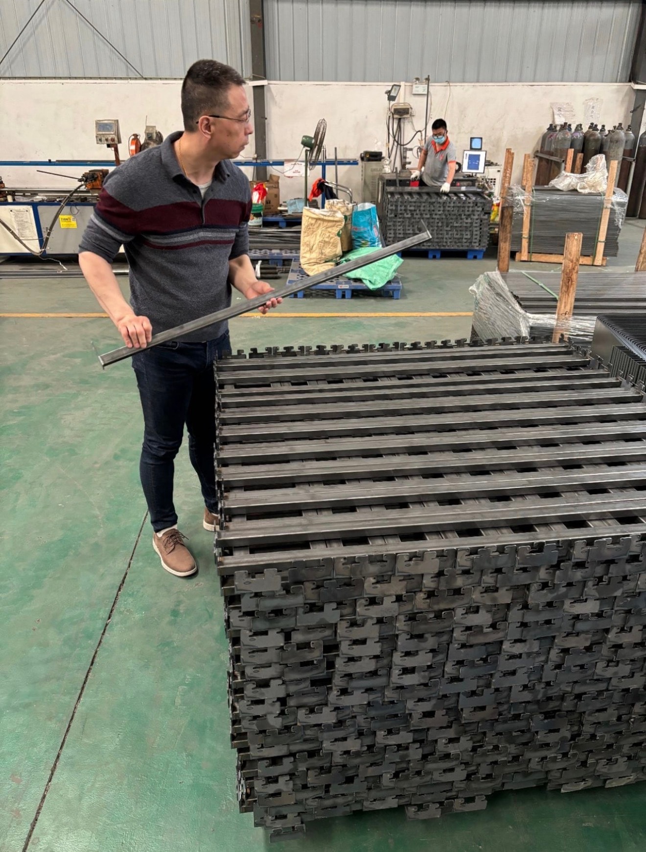 Mike Yeung examining metal grid components on the factory floor