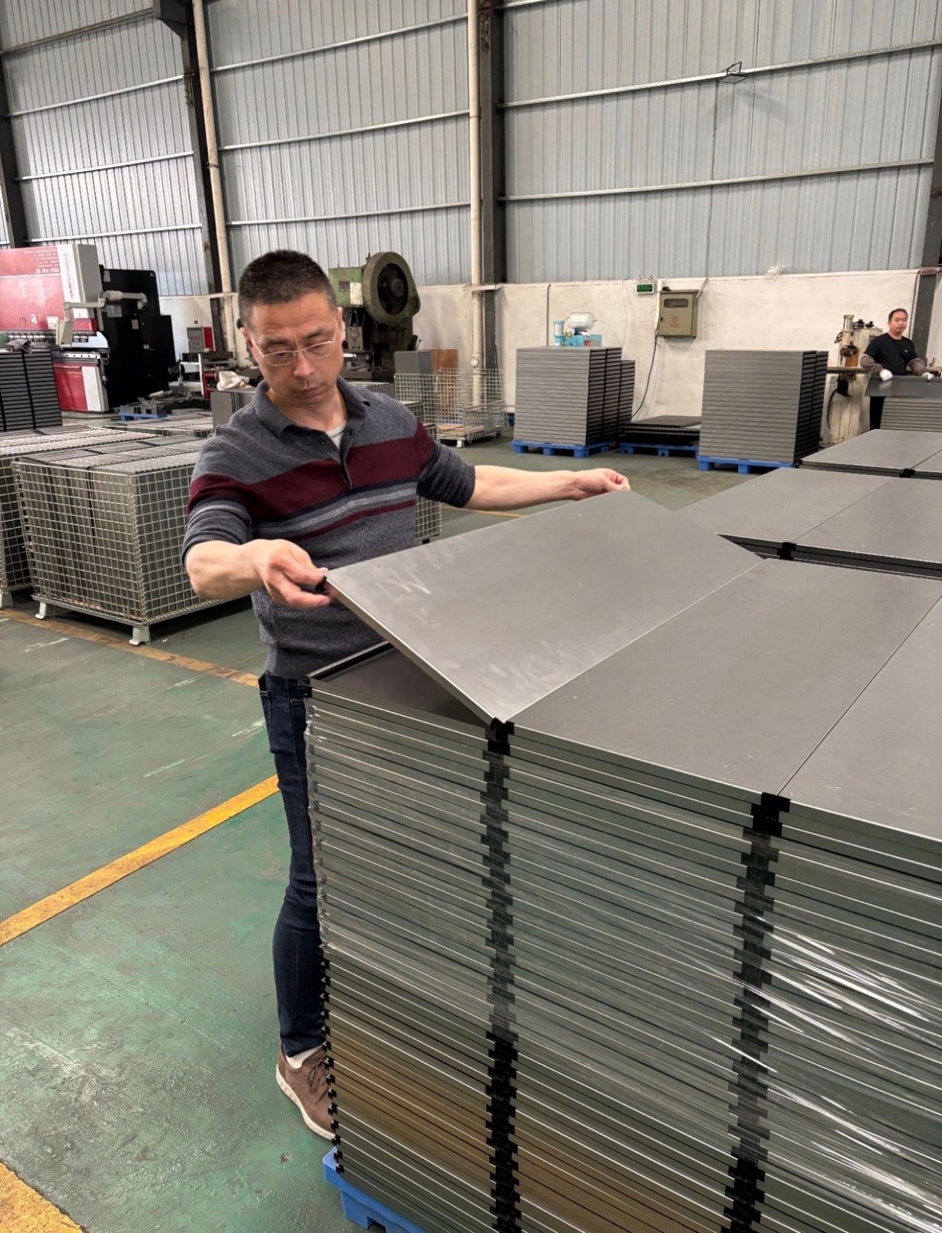 Mike Yeung inspecting sheet metal panels at a Chinese factory